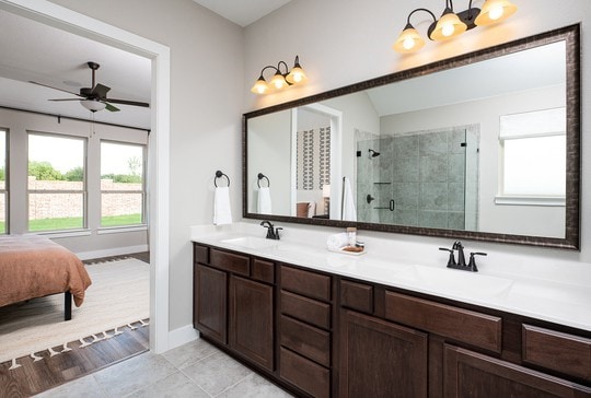 bathroom featuring tile patterned flooring, vanity, ceiling fan with notable chandelier, and a shower with shower door