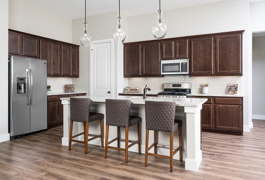 kitchen with appliances with stainless steel finishes, a kitchen island with sink, pendant lighting, and decorative backsplash