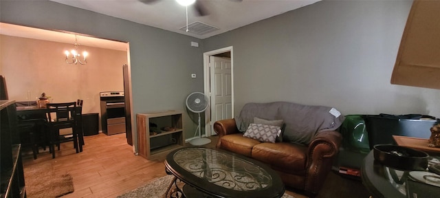 living room featuring ceiling fan with notable chandelier and light hardwood / wood-style floors