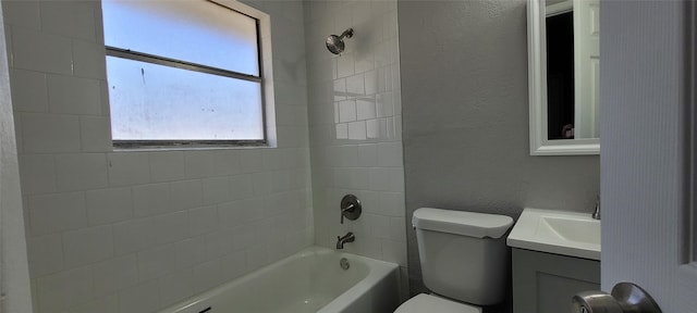 full bathroom featuring vanity, tiled shower / bath combo, and toilet