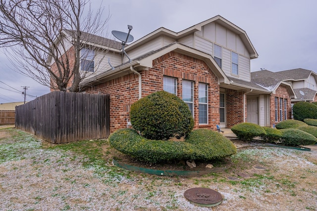 view of side of home with board and batten siding, brick siding, and fence