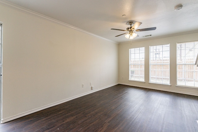 spare room featuring dark wood-style floors, visible vents, a wealth of natural light, and ornamental molding