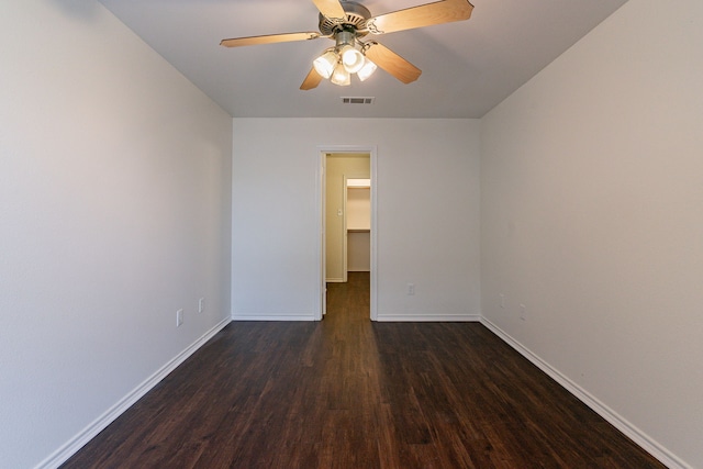 empty room featuring a ceiling fan, dark wood-style flooring, visible vents, and baseboards