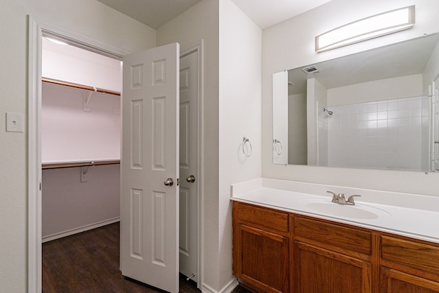 full bath with a walk in closet, wood finished floors, and vanity