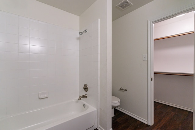 bathroom with toilet, wood finished floors, visible vents, baseboards, and shower / bathing tub combination