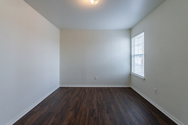 empty room featuring dark wood-type flooring and baseboards