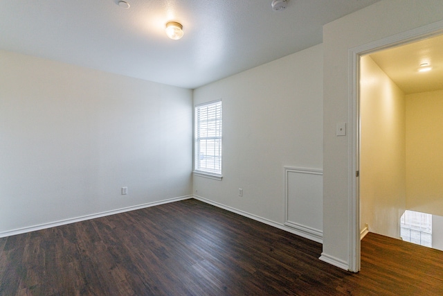 unfurnished room with dark wood-style floors, visible vents, and baseboards