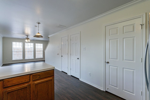 kitchen with brown cabinetry, dark wood-style flooring, decorative light fixtures, light countertops, and crown molding