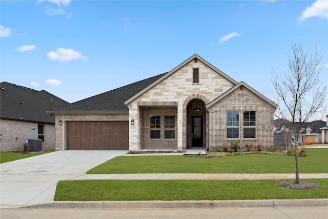 french country inspired facade featuring an attached garage, a front lawn, concrete driveway, and brick siding