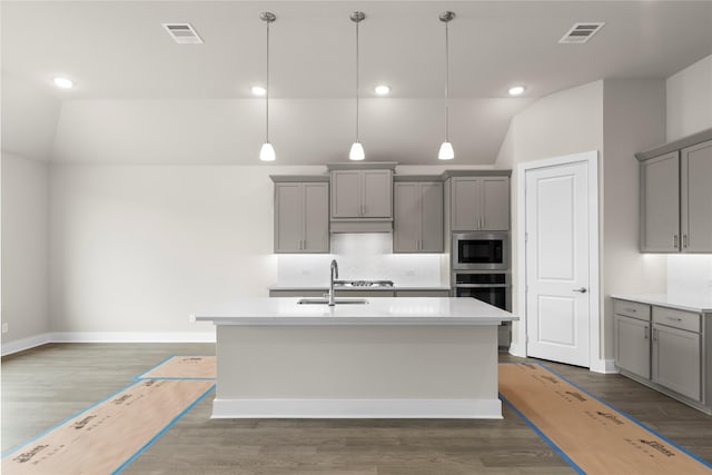 kitchen featuring a center island with sink, stainless steel appliances, visible vents, gray cabinetry, and a sink