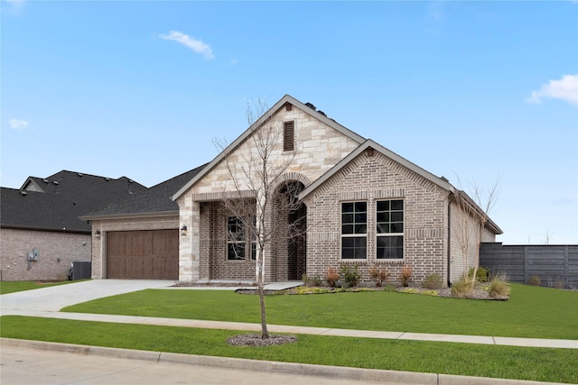 french country style house with driveway, brick siding, a front yard, and stone siding