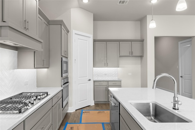 kitchen with dark wood-type flooring, stainless steel appliances, a sink, and gray cabinetry