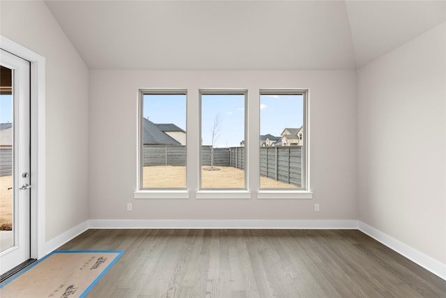 spare room with baseboards, vaulted ceiling, and wood finished floors