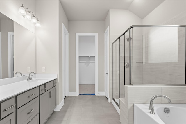 bathroom featuring vanity, baseboards, a spacious closet, a shower stall, and a bath