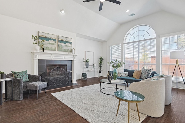 living room with dark wood-type flooring, ceiling fan, lofted ceiling, and a tiled fireplace