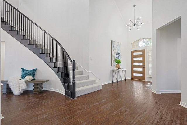 foyer with an inviting chandelier, a towering ceiling, and dark hardwood / wood-style floors