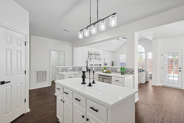 kitchen with white cabinetry, an island with sink, stainless steel dishwasher, kitchen peninsula, and dark wood-type flooring