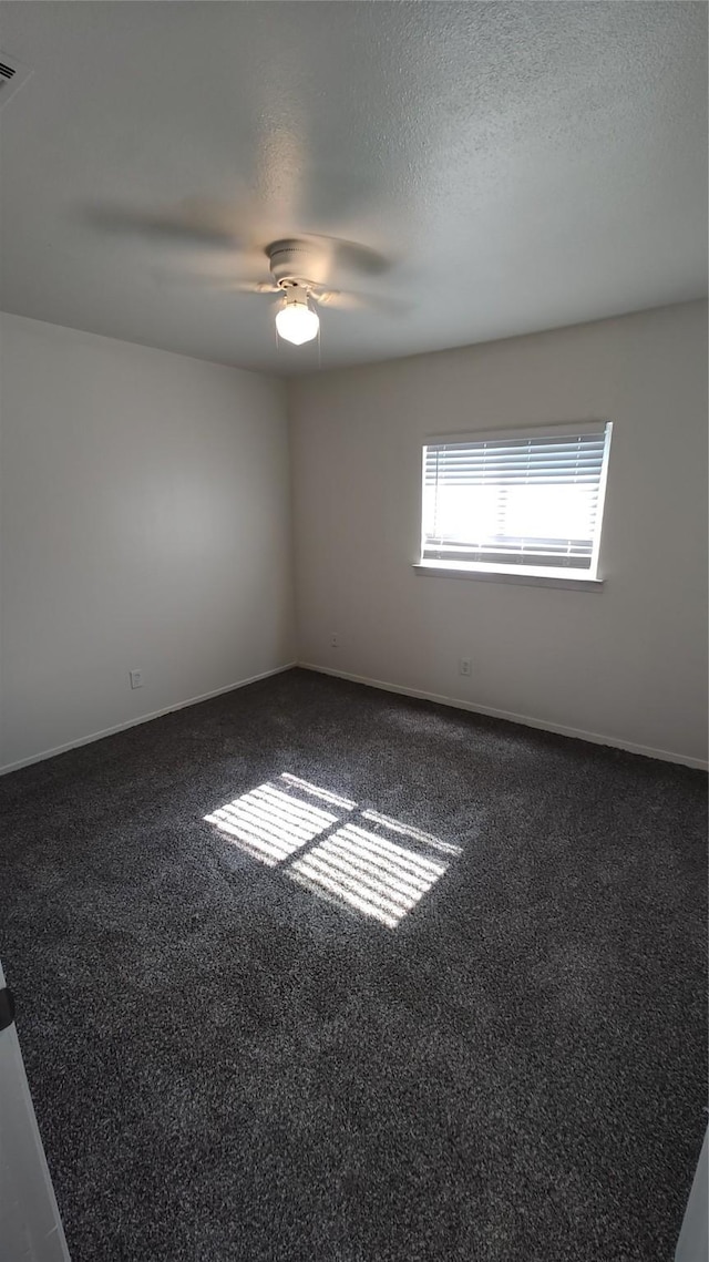 spare room with ceiling fan and dark carpet