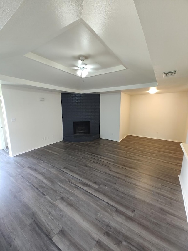 unfurnished living room featuring dark hardwood / wood-style floors, a raised ceiling, and a textured ceiling