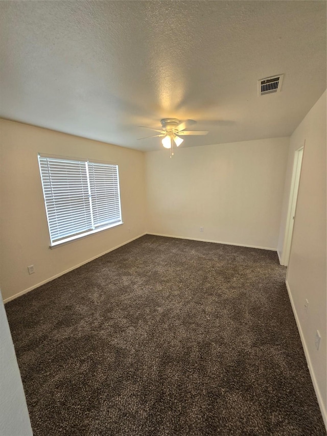 spare room featuring ceiling fan, a textured ceiling, and dark colored carpet