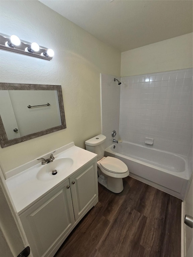 full bathroom with tiled shower / bath, vanity, toilet, and hardwood / wood-style floors