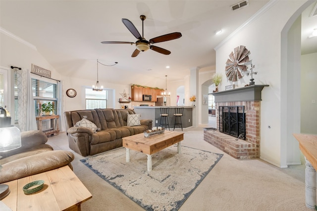 carpeted living room with crown molding, a fireplace, and ceiling fan with notable chandelier