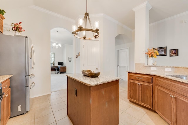 kitchen with pendant lighting, stainless steel refrigerator, light stone counters, a notable chandelier, and a kitchen island