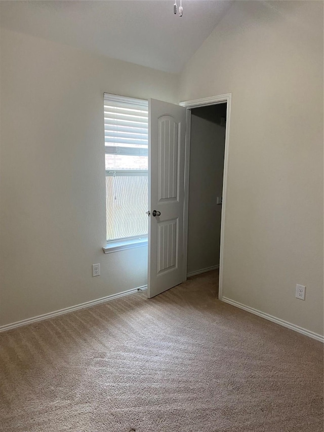 carpeted spare room with vaulted ceiling