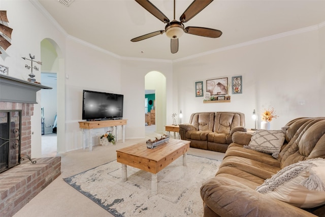 living room with ornamental molding, a brick fireplace, carpet flooring, and ceiling fan