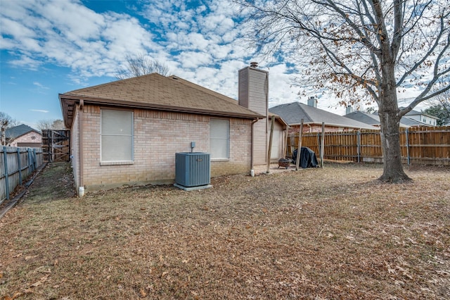 rear view of house featuring a lawn and central air condition unit