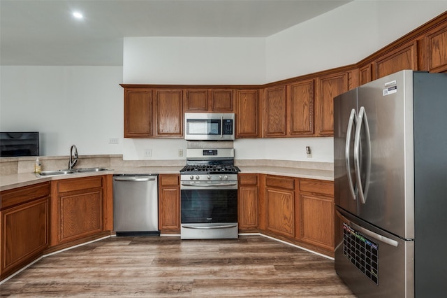 kitchen featuring stainless steel appliances, wood-type flooring, sink, and a towering ceiling