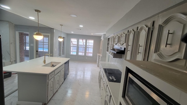 kitchen with sink, gray cabinetry, hanging light fixtures, black appliances, and a center island with sink