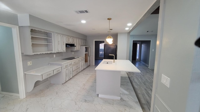 kitchen with pendant lighting, sink, a kitchen island with sink, black appliances, and white cabinets