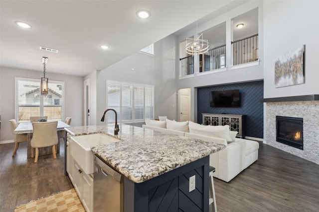 kitchen featuring sink, dishwasher, hanging light fixtures, a center island with sink, and dark hardwood / wood-style flooring