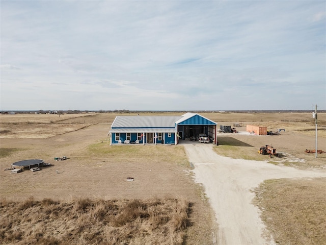 view of outbuilding with dirt driveway, a carport, and a rural view