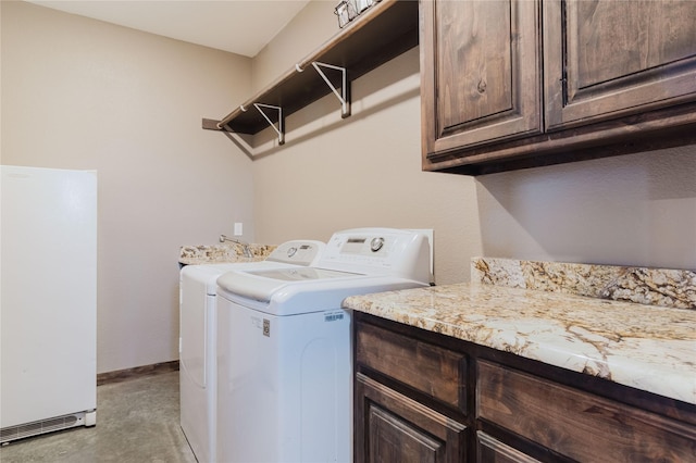 washroom featuring baseboards, washing machine and clothes dryer, and cabinet space