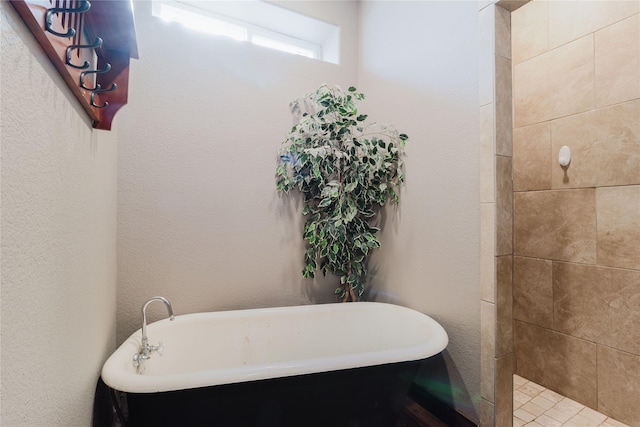 full bath featuring a freestanding tub and a textured wall