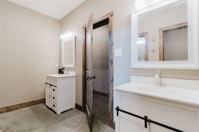 bathroom with two vanities, a sink, concrete floors, and baseboards