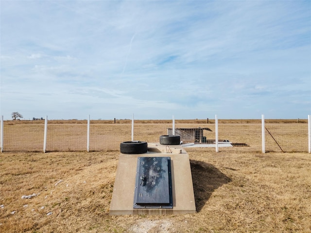 view of storm shelter with fence and a rural view