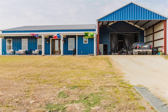 view of front of house with metal roof, a pole building, board and batten siding, a front yard, and a carport