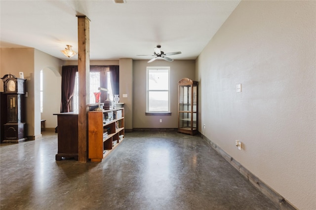 unfurnished living room with finished concrete floors, visible vents, a ceiling fan, baseboards, and arched walkways