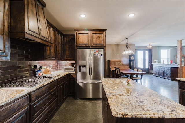 kitchen featuring light stone counters, stainless steel appliances, a center island, and dark brown cabinetry