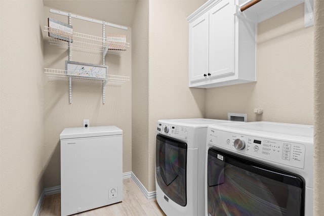 clothes washing area featuring cabinets, separate washer and dryer, and light hardwood / wood-style flooring