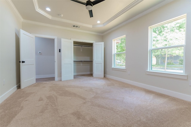 unfurnished bedroom featuring light carpet, ornamental molding, a raised ceiling, and ceiling fan