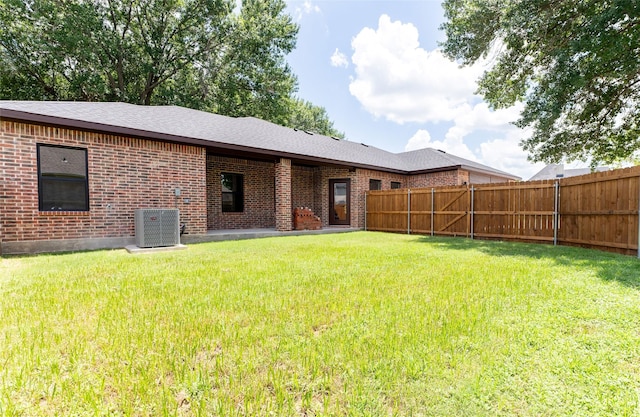 rear view of property with a yard and central AC