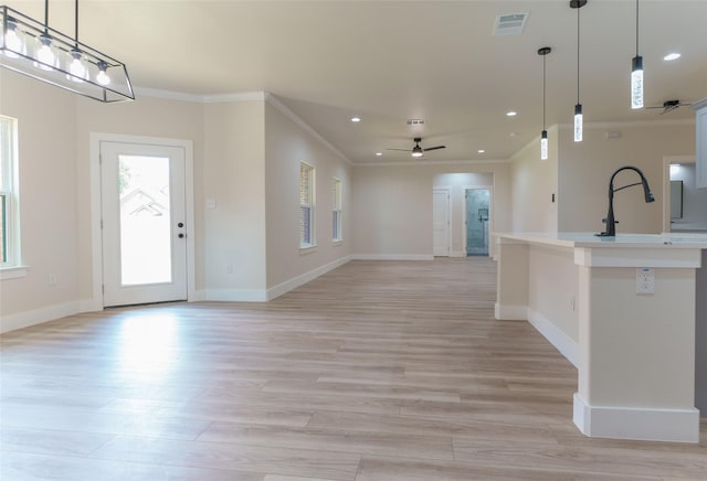 kitchen with hanging light fixtures, crown molding, ceiling fan, and light hardwood / wood-style flooring