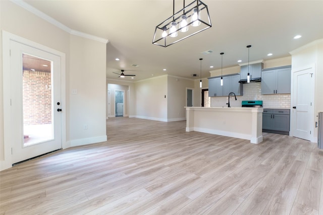 kitchen with pendant lighting, an island with sink, light hardwood / wood-style flooring, and stove