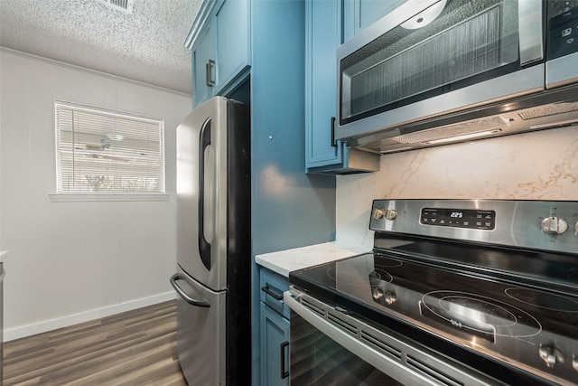 kitchen featuring blue cabinets, dark wood-style floors, stainless steel appliances, and a textured ceiling