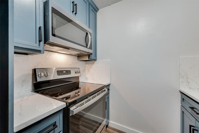 kitchen with baseboards, appliances with stainless steel finishes, blue cabinetry, and tasteful backsplash