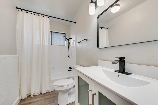 full bath with a textured wall, toilet, wood finished floors, vanity, and shower / bath combo